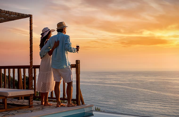 Couple on deck with wine viewing golden sunset over the ocean